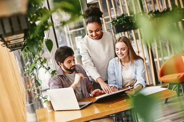 kolme nuorta asiantuntijaa työskentelemässä yhdessä pöydän ääressä