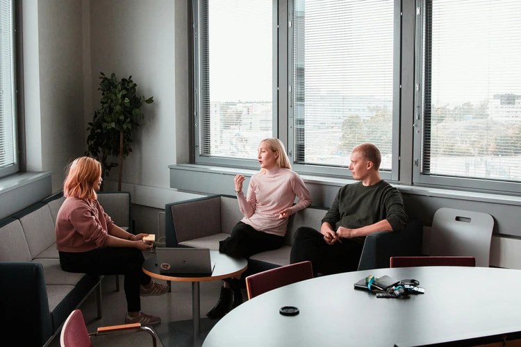 kolme ihmistä keskustelemassa sohvaryhmällä